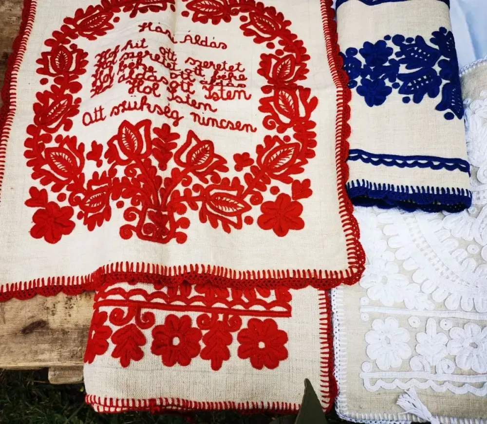 Traditionelle bestickte Tücher in Rot, Weiß und Blau mit floralen Mustern und Verzierungen.