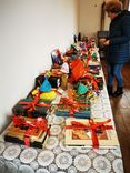 A long table full of handmade gifts and decorations, with a person in the background looking at something.